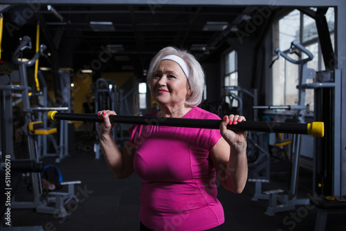 Happy healthy senior woman exercising with bodybar at the gym