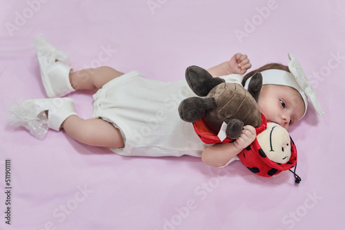 White dreesed newborn baby with her white ladybug photo