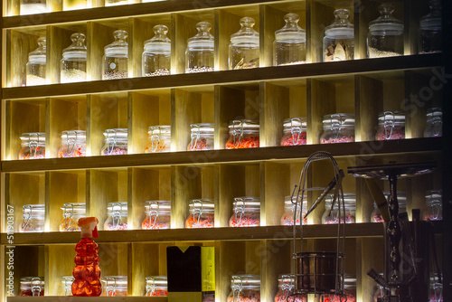 Tea and various spices in glass jars on shelves with lighting. Sale of tea in the store © ArtEvent ET