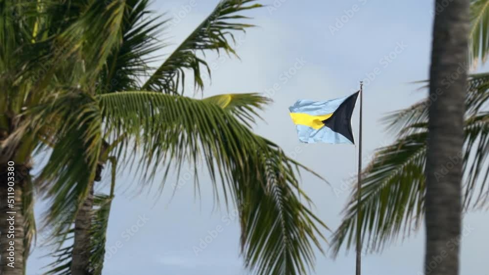 Bahamas flag blowing in the wind slow motion after recent tropical storm with ominous sky. 