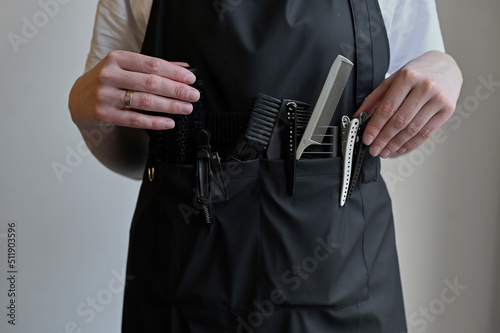 Close-up of scissors and combs in a holster box. Hairdressing tools inside a hairdresser's waist bag.