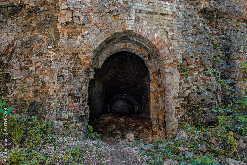 Obraz premium Military underground ruined brick tunnel entrance. Dark hole of subterranean grotto exit