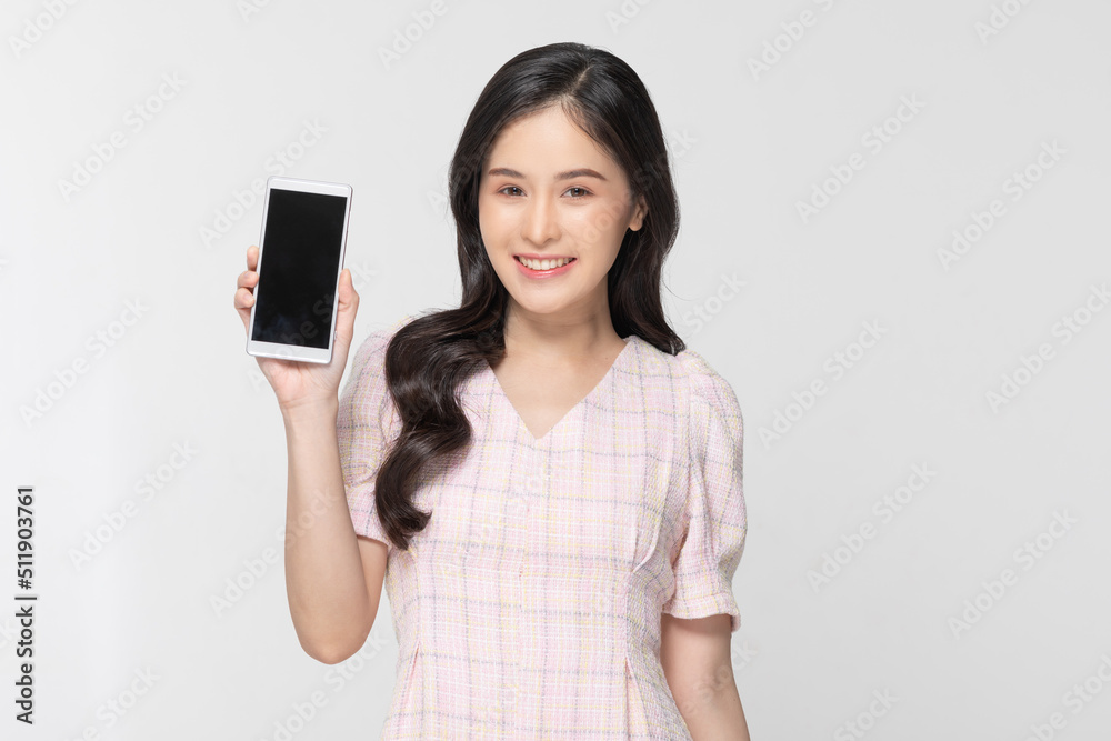 Happy attractive asian young woman smile and showing mobile phone isolated on white background. Cheerful pretty girl wear casual dress raise up smartphone to empty space for mockup to display product Happy attractive asian young woman smile and showing mobile phone isolated on white background. Cheerful pretty girl wear casual dress raise up smartphone to empty space for mockup to display product