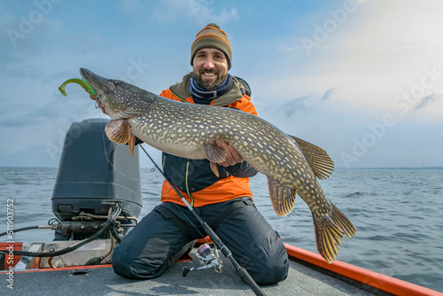Successful pike fishing. Happy fisherman hold huge muskie fish photo