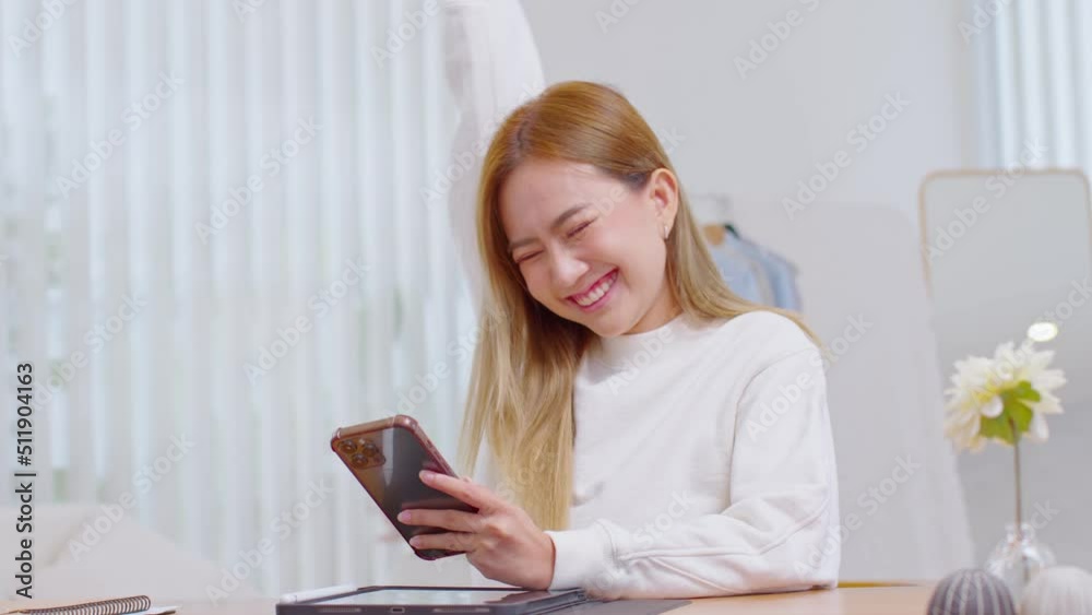Millennial asian young woman looking mobile phone laughing with good news or discount voucher for shopping online at home.Happy and cheerful woman looking on cellphone app read message feel excited Millennial asian young woman looking mobile phone laughing with good news or discount voucher for shopping online at home.Happy and cheerful woman looking on cellphone app read message feel excited