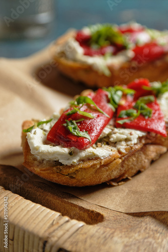 Crostini with marinated bell pepper strips on herb cream cheese. Close-up view.
