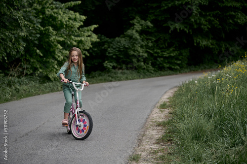 happy cheerful child girl riding a bike in Park in the nature. © jul14ka