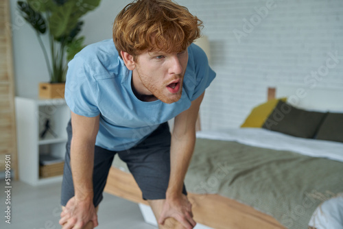 Young redhead man looking exhausted after training at home