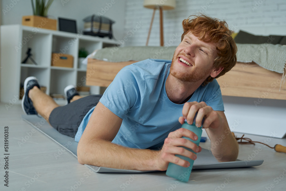 Handsome redhead man looking tired and happy after training at home Handsome redhead man looking tired and happy after training at home