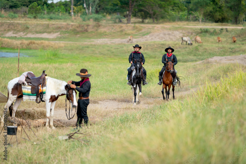 Fototapeta premium Two cowboys on horses are riding to the village after finish take care of cow in background.