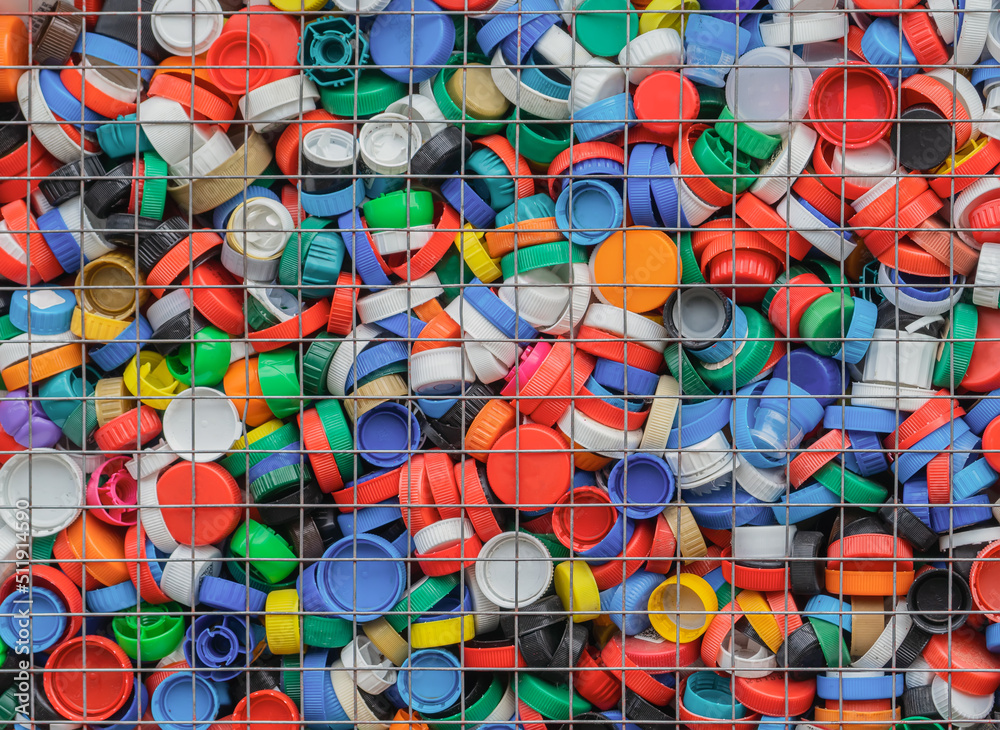 Large number of plastic caps in a lattice container. Separate garbage collection. Plastic recycling.
