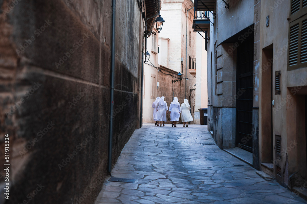 nans walking down a narrow street in the town mallorca
