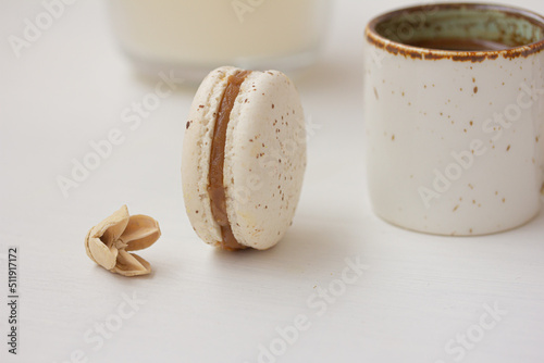 White macaron, cup of coffee on white background. Salted caramel macaroon