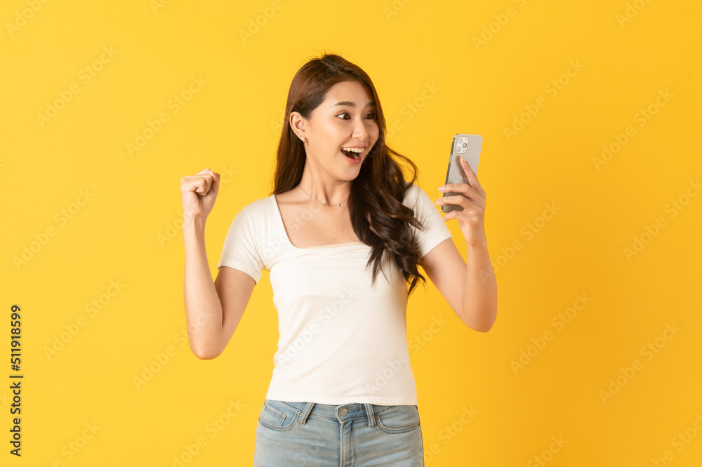 Surprise asian beautiful woman isolate on yellow background using smartphone
