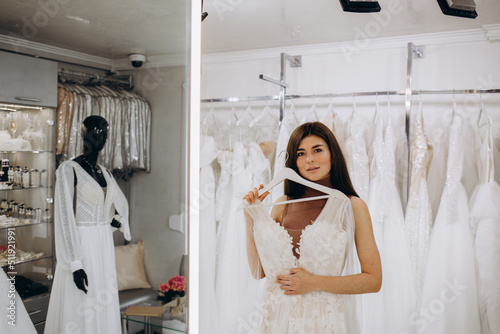 Young woman choosing wedding dress in salon