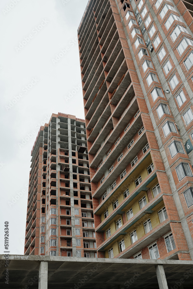 Fototapeta premium Below shot of blocks of flats or highrise condos built up by modern architectural project in central region of city with grey sky above