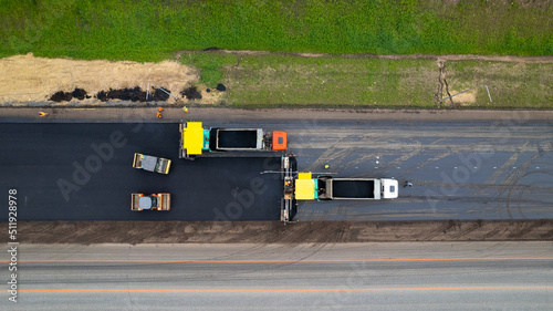 Road construction works aerial view. Laying of new asphalt on the road. The paver lays fresh asphalt, road rollers level and compact asphalt. Road construction equipment, view from a height