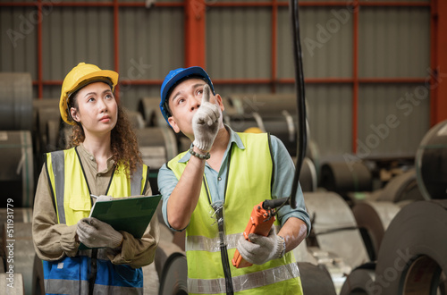 Professional senior Asian man worker holding push button switch and coaching crane operation for a woman worker in factory industry.