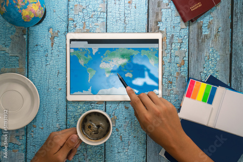 A man's hand holds a pencil that points to a location on a map on a tablet.Vacation planning ahead.Travel concept © Small365