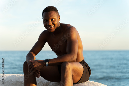 Shirtless man at beach enjoying of the sun while smiling to the camera