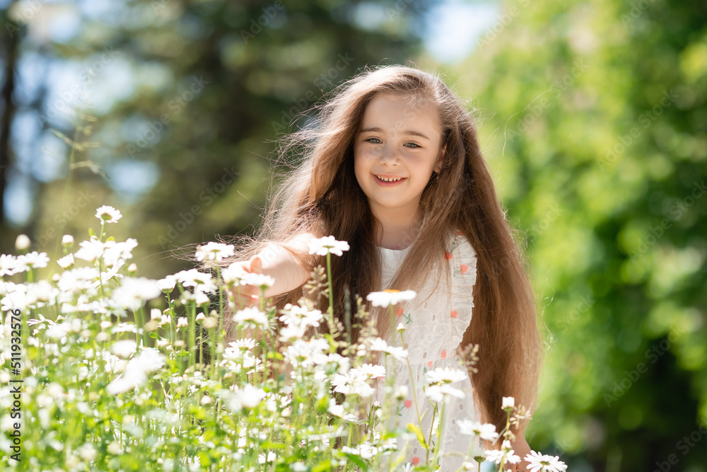Beautiful Little girl in white dress with flowers in park summertime Beautiful Little girl in white dress with flowers in park summertime