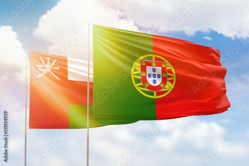 Sunny blue sky and flags of portugal and oman