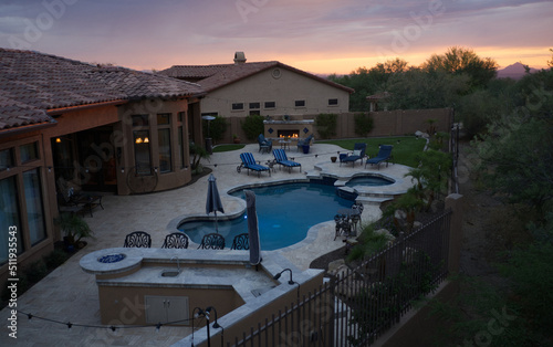 an aerial view of a desert landscaped house in Arizona featuring a travertine tiled pool deck and outdoor kitchen.