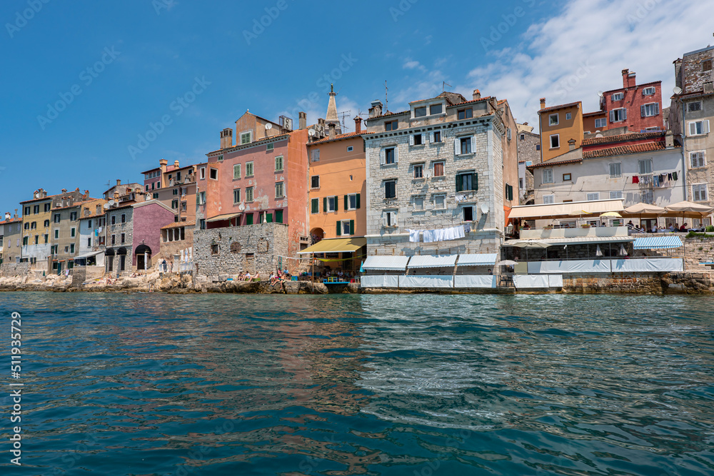 Old Croatian Rovinj city view from the sea with laundry drying by the windows and people on the cafe terrasses enjoying the view. 2022