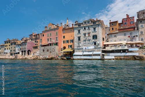 Old Croatian Rovinj city view from the sea with laundry drying by the windows and people on the cafe terrasses enjoying the view. 2022