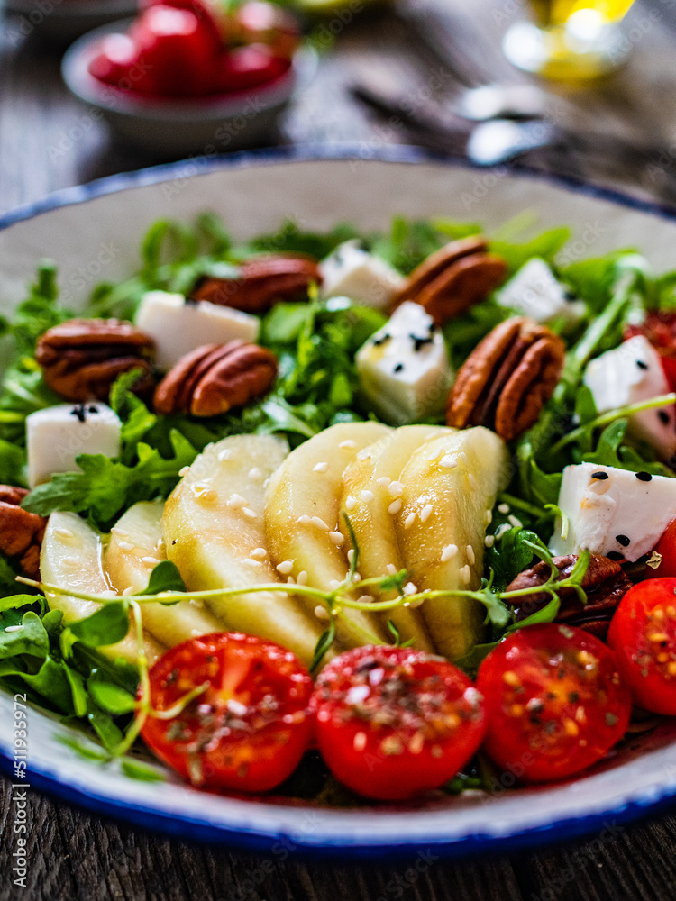 Fresh salad - goat cheese, pear and vegetables on wooden table
Fresh salad - goat cheese, pear and vegetables on wooden table