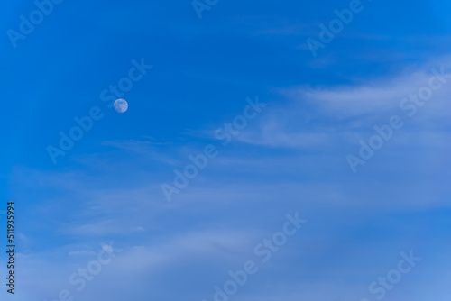 abstract background of fluffy clouds and the moon on a blue evening sky