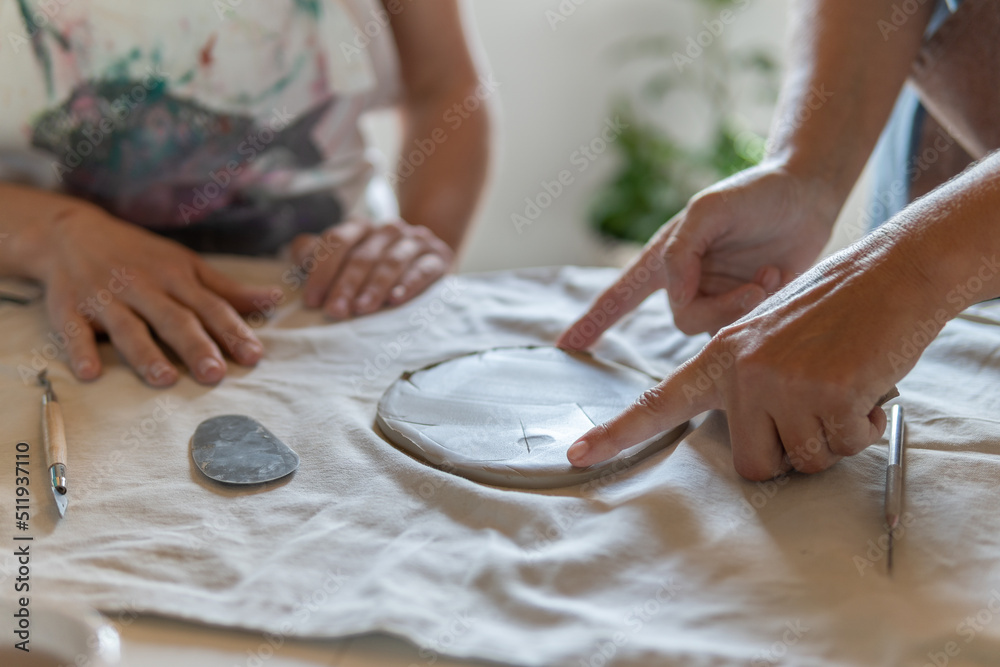 An adult potter showing the student how make a ceramic plate. An adult potter showing the student how make a ceramic plate.
