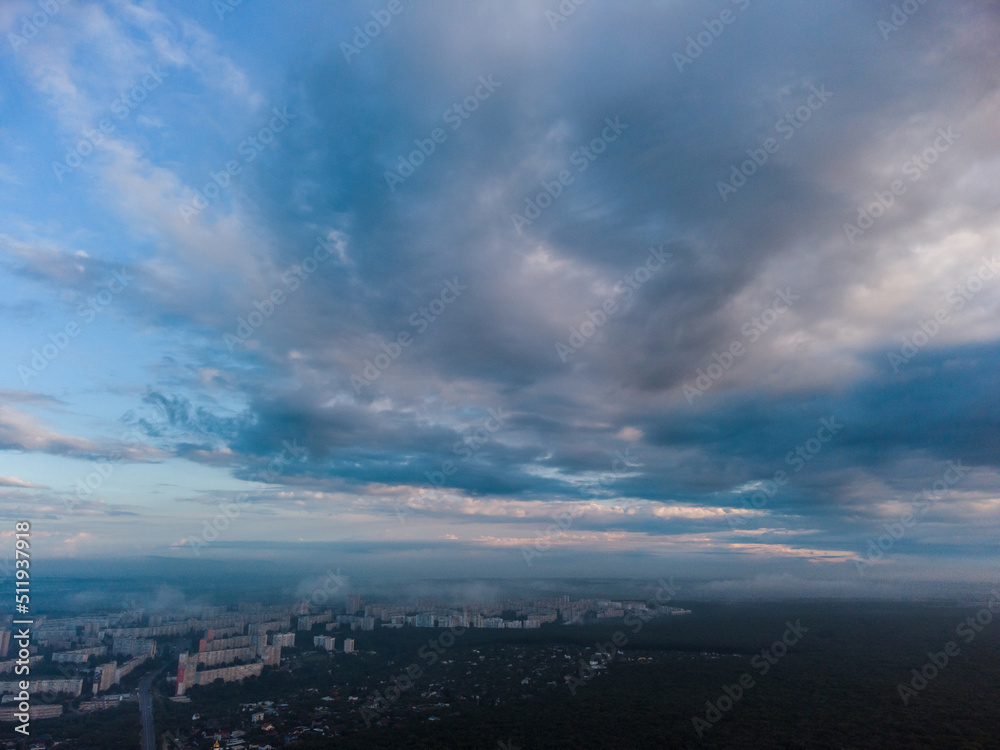 Peaceful morning cloudy view in summer city residential district. Aerial cloudscape above forest near Kharkiv streets, Ukraine