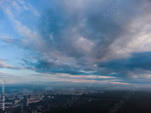 Peaceful morning cloudy view in summer city residential district. Aerial cloudscape above forest near Kharkiv streets, Ukraine