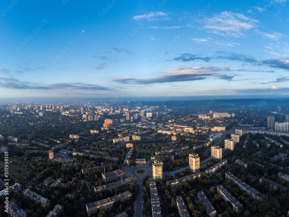 Early morning cityscape panorama view in summer green city, residential district with moon in blue sky. Aerial cityscape above buildings and streets, Pavlovo Pole, Kharkiv Ukraine