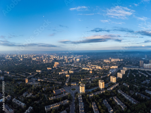 Early morning cityscape panorama view in summer green city, residential district with moon in blue sky. Aerial cityscape above buildings and streets, Pavlovo Pole, Kharkiv Ukraine © Kathrine Andi