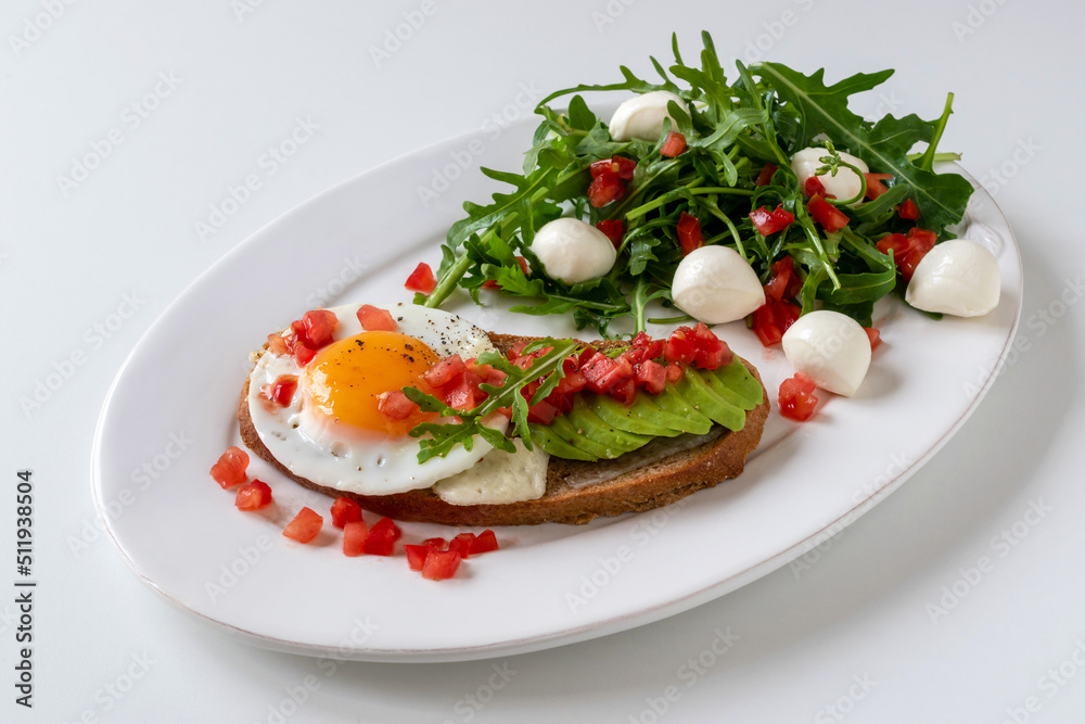 Sandwich with cheese, fried egg and avocado for breakfast. Arugula with mozzarella with finely chopped tomatoes. Sandwich with cheese, fried egg and avocado for breakfast. Arugula with mozzarella with finely chopped tomatoes.