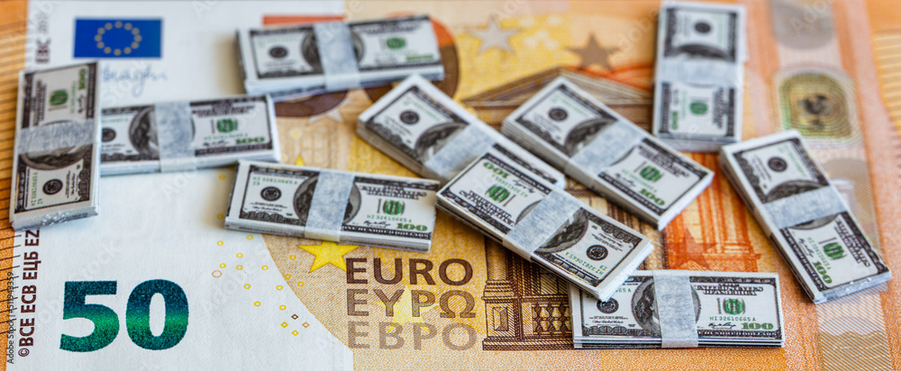 bundles of miniature 100 dollar banknotes on 50 euro banknote background
