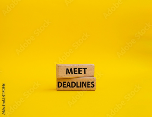 Meet Deadlines symbol. Concept word Meet Deadlines on wooden blocks. Beautiful yellowbackground. Business and Meet Deadlines concept. Copy space