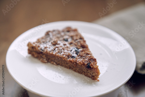 Close-up of a piece of lemongrass with blueberries and cranberries without milk and eggs on flaxseed flour. Part of the pie is on a white plate. The concept of healthy eating