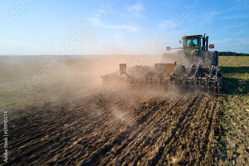 Fototapeta Aerial view of tractor plowing agriculural farm field preparing soil for seeding