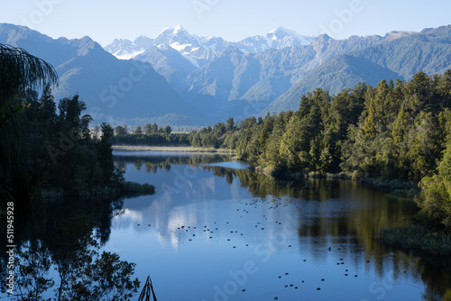 Perfect reflection in Lake Matheson surrounded by beautiful natural forest under blue sky © Brian Scantlebury
