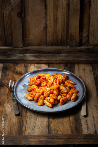 Italian potato Gnocchi with tomato sauce. Rustic style, wooden background