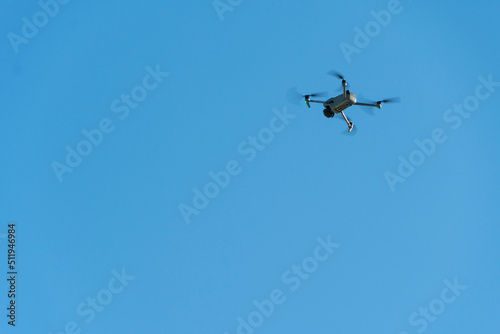 A modern drone against a clear blue sky. The quadcopter hovered motionless in the sky. The use of aircraft for reconnaissance and fire correction.