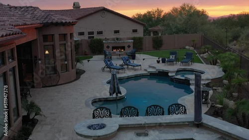 A 4k aerial view of a desert landscaped home in Arizona featuring a travertine tiled pool deck.