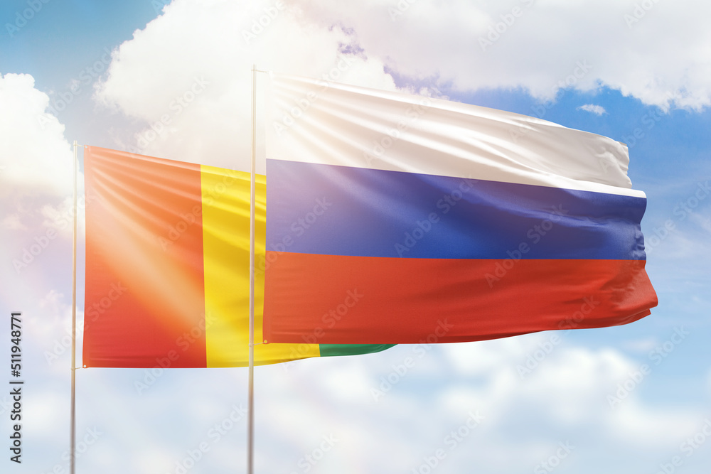 Sunny blue sky and flags of russia and guinea Sunny blue sky and flags of russia and guinea