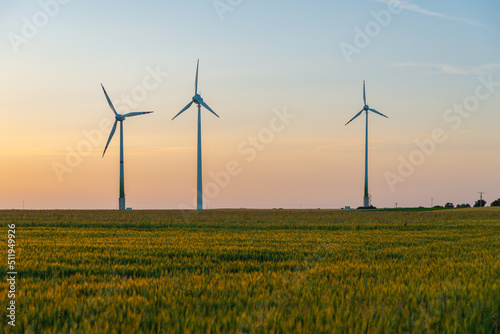 View of wind power turbines, part of a wind farm. Wind turbines on green field in countryside. Wind power plant.