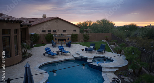 An Ariel view of a desert landscaped home in Arizona featuring a travertine tiled pool deck and outdoor fireplace.