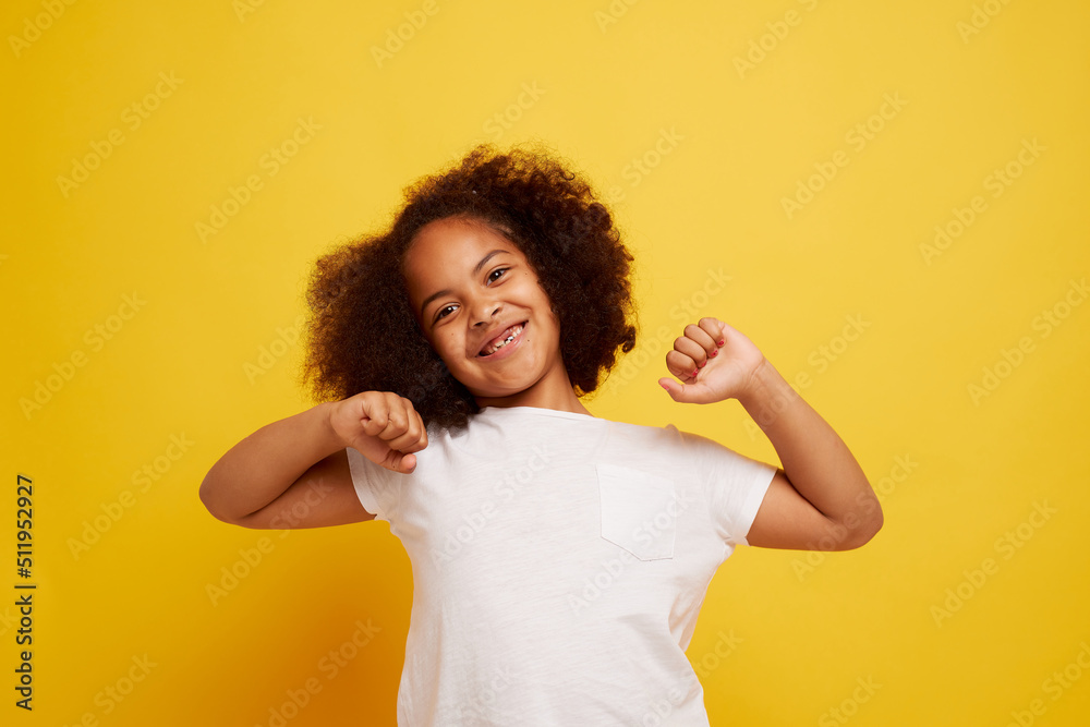 portrait of a young African girl smiling and rejoicing on a clean yellow background