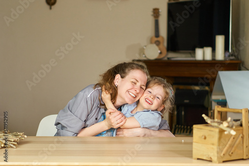 Have fun together. Smile and laugh at home. Happy family at table. Motherhood is joy. Children laughter. Kid play. woman babysitter is good for sister. White dresses on caucasian women. tickles girl